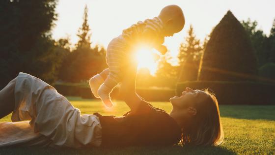 母亲和婴儿在阳光下玩耍的照片