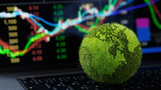 绿色地球仪在笔记本电脑键盘上与股票图形在笔记本电脑屏幕上