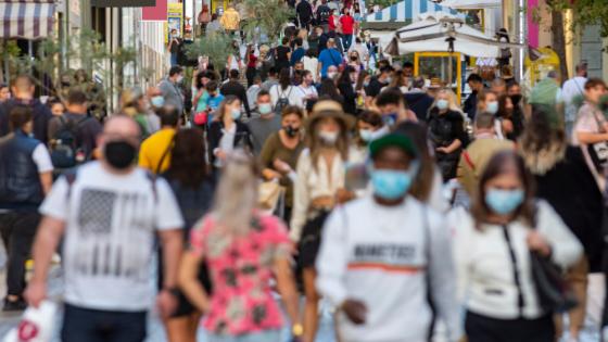 人群上升和下降一个繁忙的购物街穿着防护面具