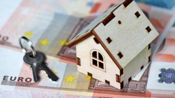 欧元钞票背景上的木屋模型和钥匙。