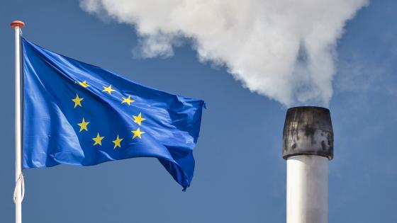 欧盟旗帜旁边工厂烟囱排放烟雾